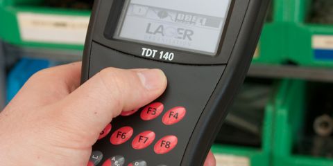 Foto einer Hand, die die Scan-Taste eines Handterminals TDT 140 drückt.